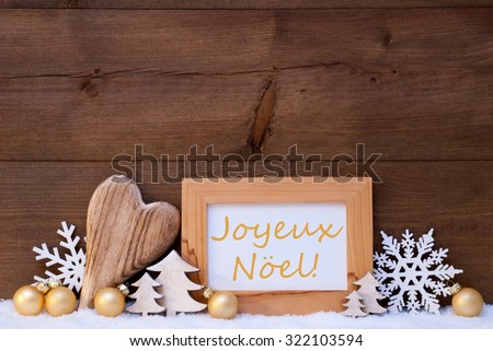 Golden Christmas Decoration On Snow. Heart, Christmas Tree Balls, Snowflake, Christmas Tree. Picture Frame With FrenchText Joyeux Noel Mean Merry Christmas. Rustic, Vintage Wooden Background. 