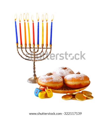 image of jewish holiday Hanukkah with menorah (traditional Candelabra), donuts and wooden dreidels (spinning top).isolated on white
