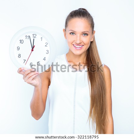 young happy girl posing in studio and holding white clock isolated on white background.