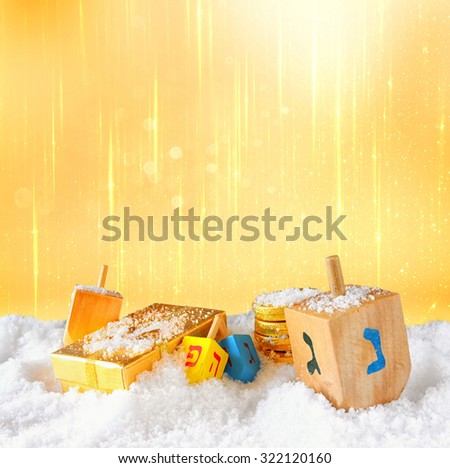 image of jewish holiday Hanukkah with wooden colorful dreidels (spinning top) and chocolate traditional coins over december snow. glitter background
