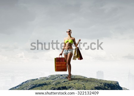 Young pretty woman in bikini and shorts with shopping bags