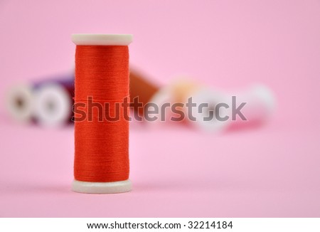 Orange thread with a pile of colorful spools in the background
