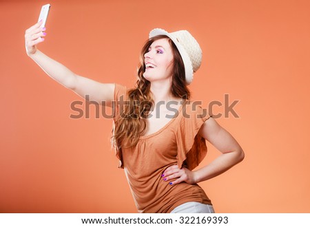 Technology internet and happiness concept. Young summer woman taking self picture selfie with smartphone camera orange background