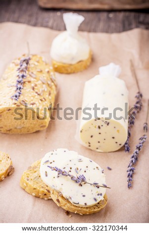 Homemade fresh butter with lavender flowers in parchment on the wooden background. The concept of natural organic food. selective Focus