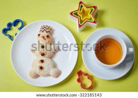 Picture of snowman on white plate with colorful molds tea isolated on green background copy space