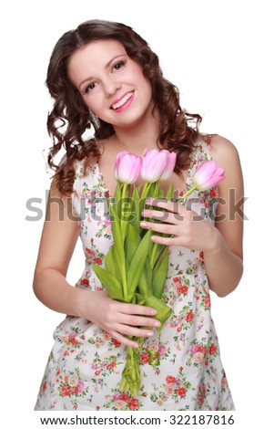 Positive young girl with a charming smile, holding a bouquet of tulips 