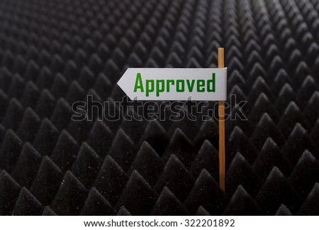 white directional sign saying APPROVED on bumpy black background
