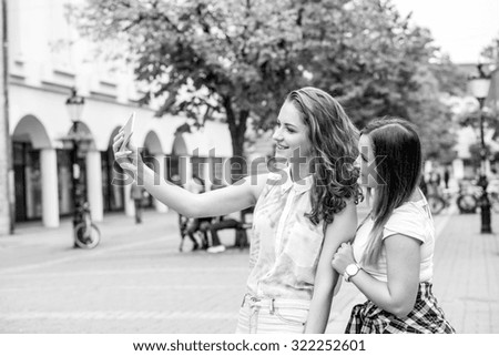 two girlfriends taking selfie photo with mobile phone, black and white photo