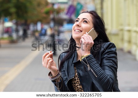 black hair smoking woman talking on phone on street