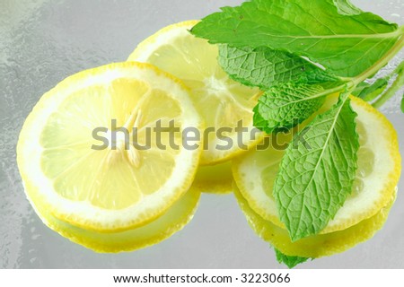 Fresh chilled sliced lemons and mint on a reflective background with a shallow depth of field