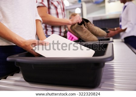 Man Puts Digital Tablet Into Tray For Airport Security Check Royalty-Free Stock Photo #322320824