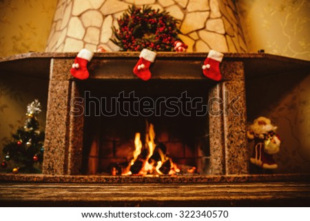 Warm cozy fireplace decorated for Christmas with real wood burning in it. Cozy Christmas concept. Christmas background with space for your text.