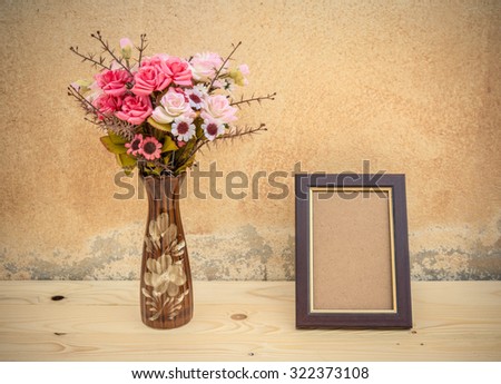 Vase with flowers and picture frame on a wooden table,vintage style, still life