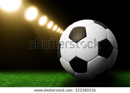 Soccer ball on green stadium, arena in night illuminated bright spotlights