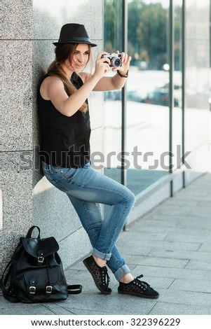 The stylish girl student travels with the mirrorless digital camera. City scene