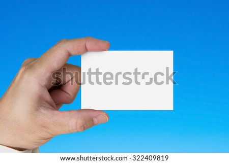 Hand holding blank white name card, isolated on blue background
