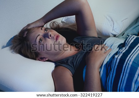 sleep disorder, insomnia. young blonde woman lying on the bed awake Royalty-Free Stock Photo #322419227