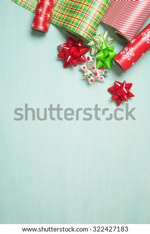 Christmas Gift Wrapping Party Time with Red and Green Colorful Paper and Ribbon Bows on Cyan Blue Shabby Chic Wood Board Background with Room or Space for copy, text, your Holiday Greeting words.  