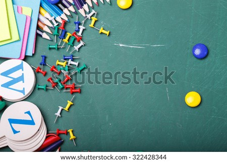 Palette set of colorful sharp pencils brown red yellow blue violet pink purple lilac grey black white and orange colors lying in row with other school tools on green background copyspace, horizontal