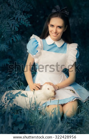 Girl Costumed as Alice in Wonderland with The White Rabbit - Portrait of a smiling girl in a blue costume holding a white bunny
