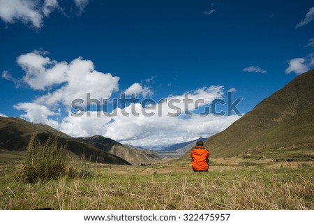 A young traveler sit and watch beautiful landscape in Tibet, China