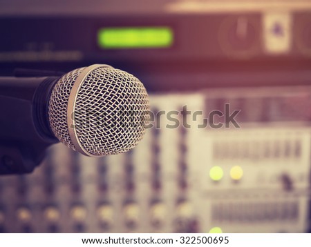 Vintage style photo of the microphone in a recording studio or concert hall with amplifier equipment in out of focus background. : Filtered process.