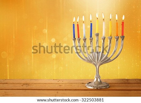 Image of jewish holiday Hanukkah background with menorah (traditional candelabra) and Burning candles with glitter overlay
