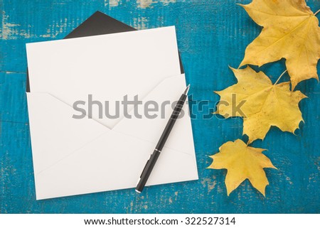  Envelope, pen and autumn leaves on wooden background
