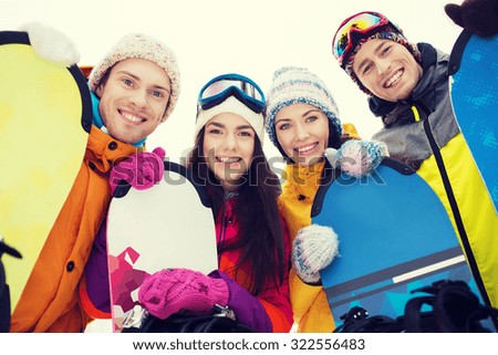 winter, leisure, extreme sport, friendship and people concept - happy friends with snowboards