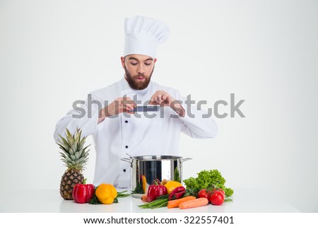 Portrait of a handsome male chef cook making photo of food isolated on a white background