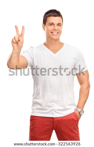 Vertical shot of a young man making a peace hand gesture and looking at the camera isolated on white background