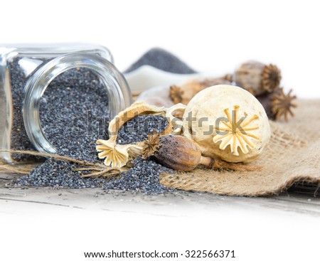 Photo of glass spicebox full of poppy seeds on burlap with white space