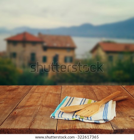 Kitchen utensils on tablecloth and old wooden table in front of romantic Provence rural landscape. retro filtered image
