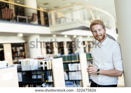 Handsome intelligent male student smiling in library