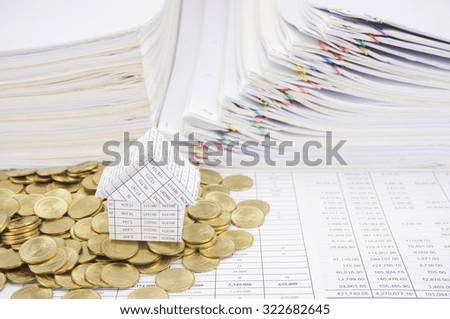 House with stack of gold coins on finance account have paper of report and step overload of old paperwork as background. Business and finance concepts rich and successful photography.