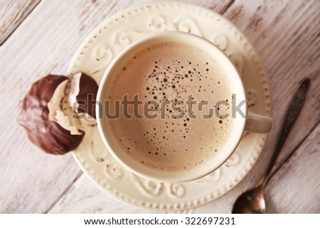 Cup of coffee with chocolate zephyr on wooden table, top view