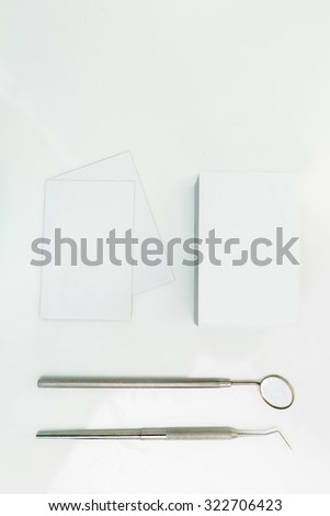 Business cards near dental tools on white background