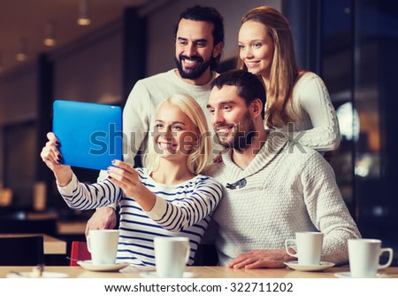 people, leisure, technology and friendship concept - happy friends with tablet pc computer taking selfie at cafe