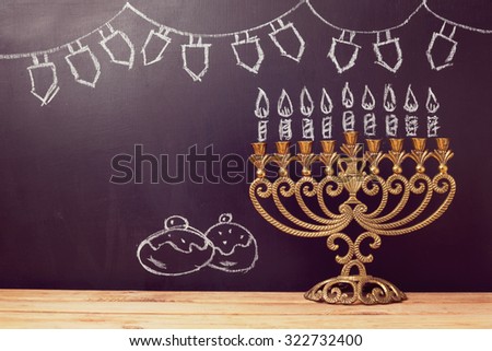 Jewish holiday Hanukkah background with menorah over chalkboard with hand sketched symbols