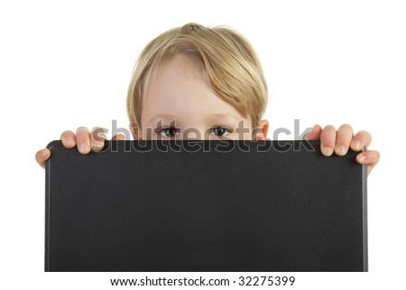 A young boy peers out from behind a laptop computer. Isolated on a white background.