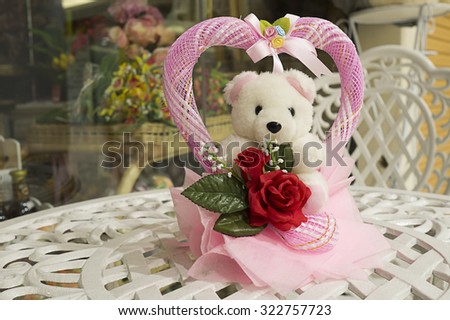 White bear doll and pink heart with red rose on the vintage white table. Love and wedding concept