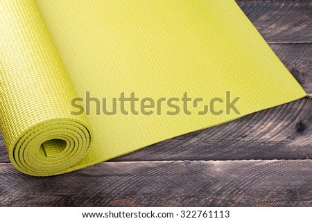 Yoga mat on a wooden background. Equipment for yoga. Concept  healthy lifestyle. Lots of copyspace. Selective focus Royalty-Free Stock Photo #322761113