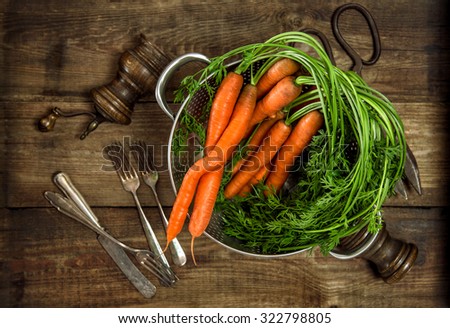 Carrots with green leaves on rustic wooden background. Vegetable. Country food concept. Vintage style toned picture
