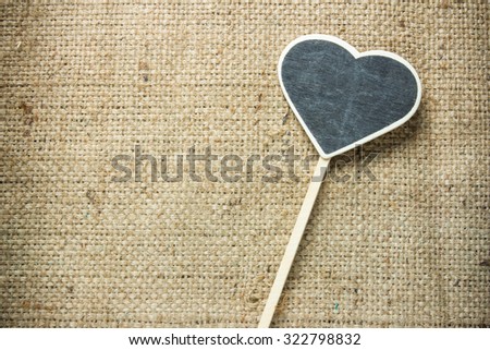 Blackboard wooden plaque placed right-sided heart on sackcloth.