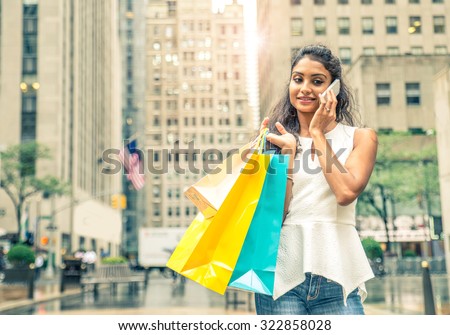 Young attractive woman walking on the streets with shopping bags - Asian girl shopping while calling her friend with cellular phone 