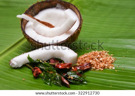 Coconut Kashmiri chilli/chilly, curry leaves, fried grated coconut on banana leaf top view. cooking, frying, seasoning sambar, chutney. coconut oil is used in soaps, cosmetics. red chilly Kerala India