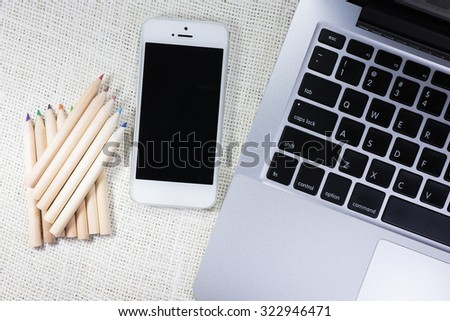 Mobile,colorful pencils and laptop on sackcloth background, Work space for designer or hipster style.