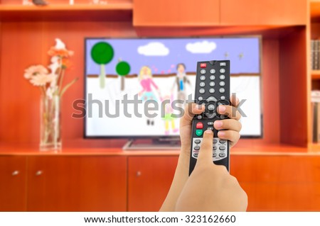 Hand of children holding television remote and watching cartoons and animated