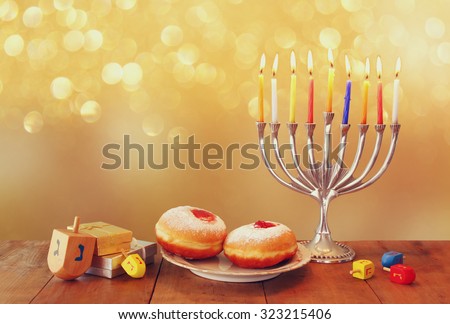 image of jewish holiday Hanukkah with menorah (traditional Candelabra), donuts and wooden dreidels (spinning top) 