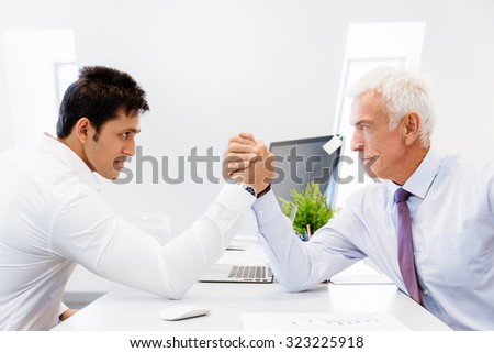 Two businessmen competeting arm wrestling in office